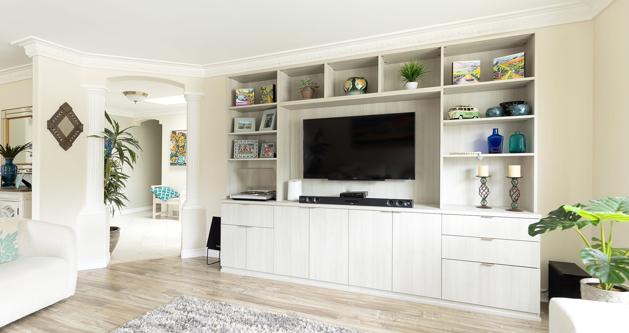 Custom home solution for your living area with a white entertainment center, side floating shelves and cabinets custom designed by California Closet.