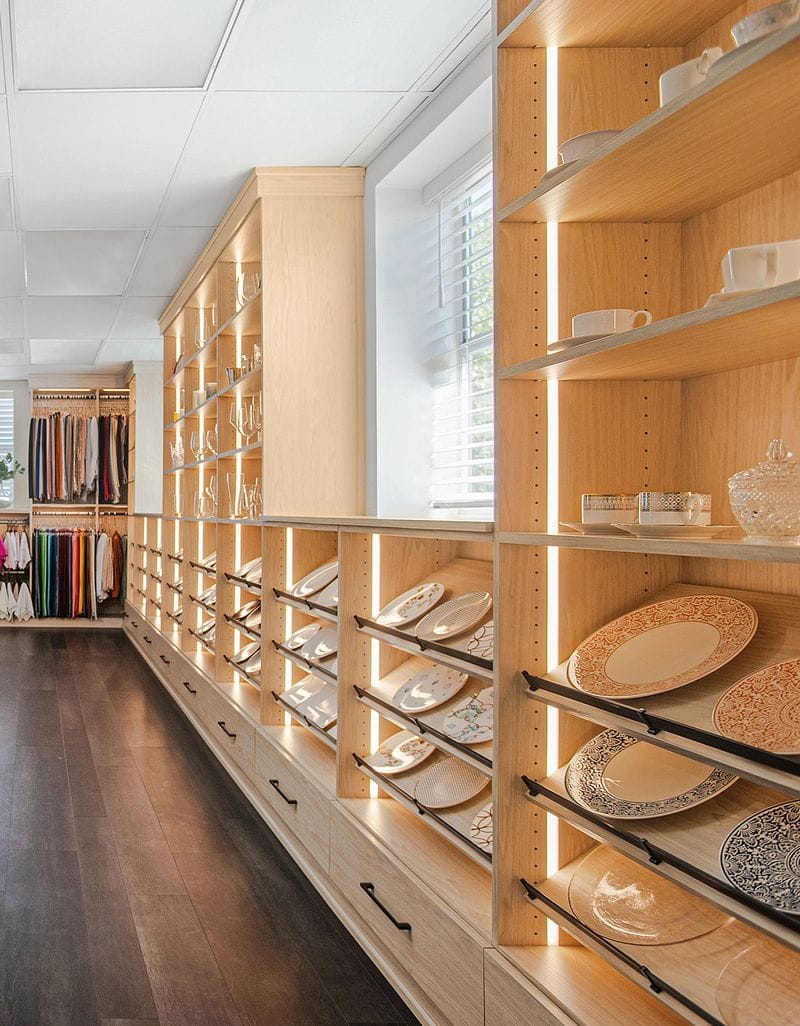 Commercial showroom with open shelving row, illuminated with LED lighting and custom drawers for storage California Closets