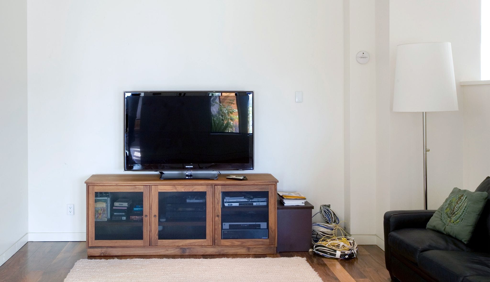 Before lounge area with no media storage and outdated entertainment center to be installed by California Closets