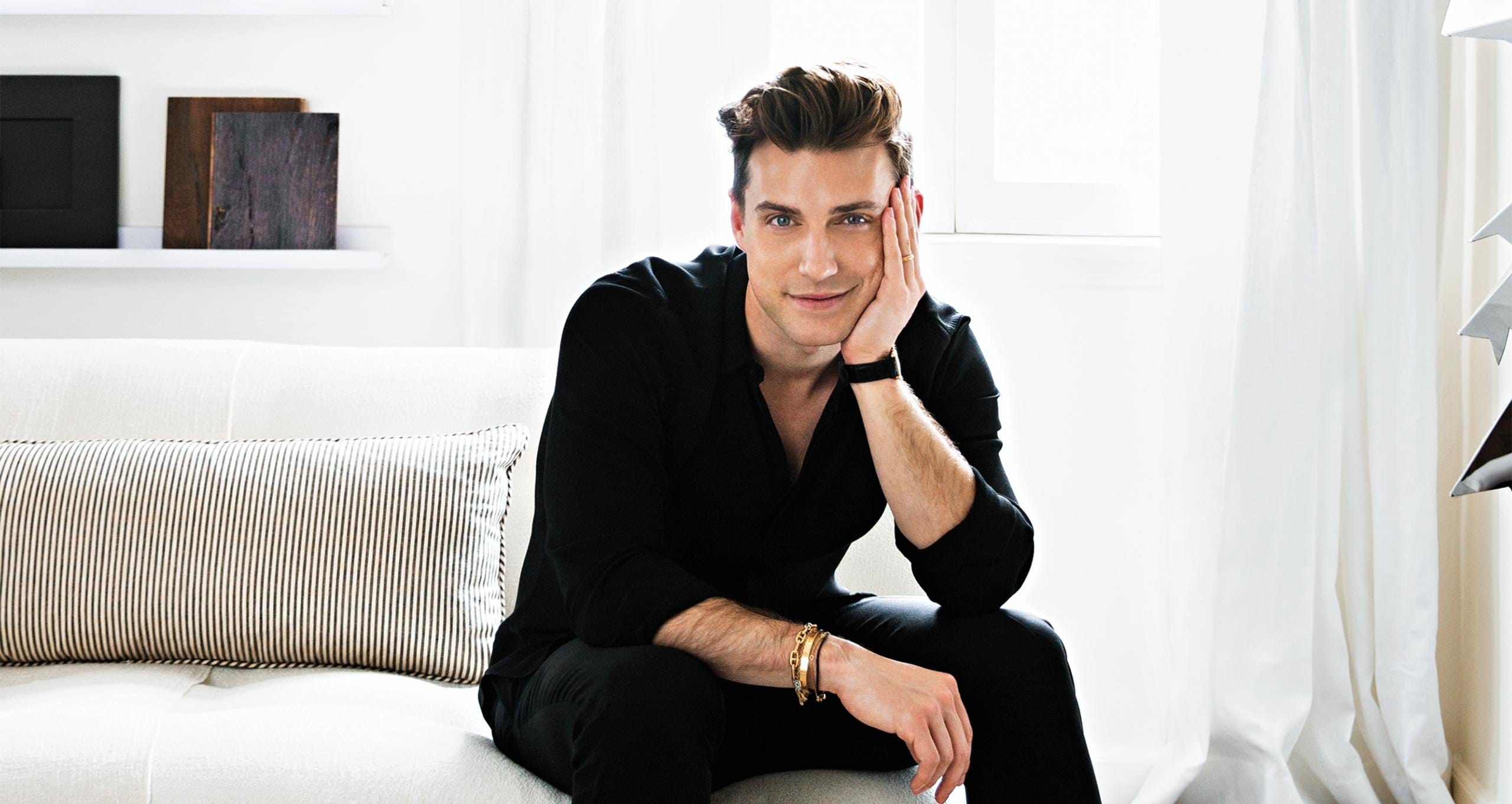 Jeremiah Brent in his Beverly Grove home with crisp white soafa, walls and striped pillow in Ideas of Order Magazine
