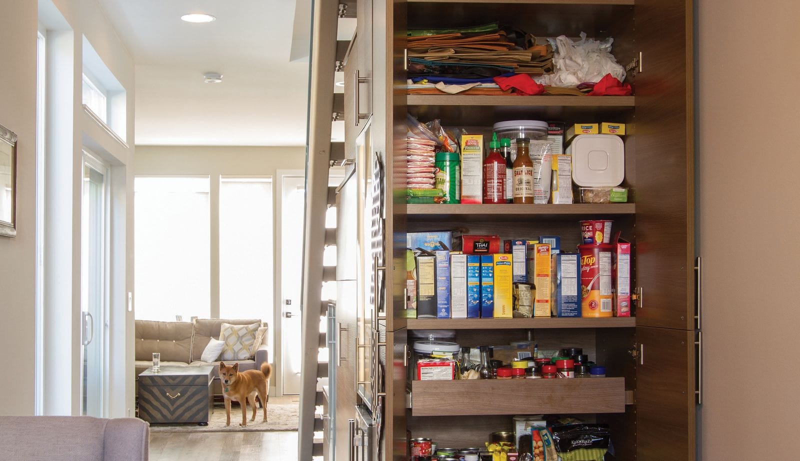 Understairs kitchen pantry designed with custom shelves and pull out drawers by California Closets